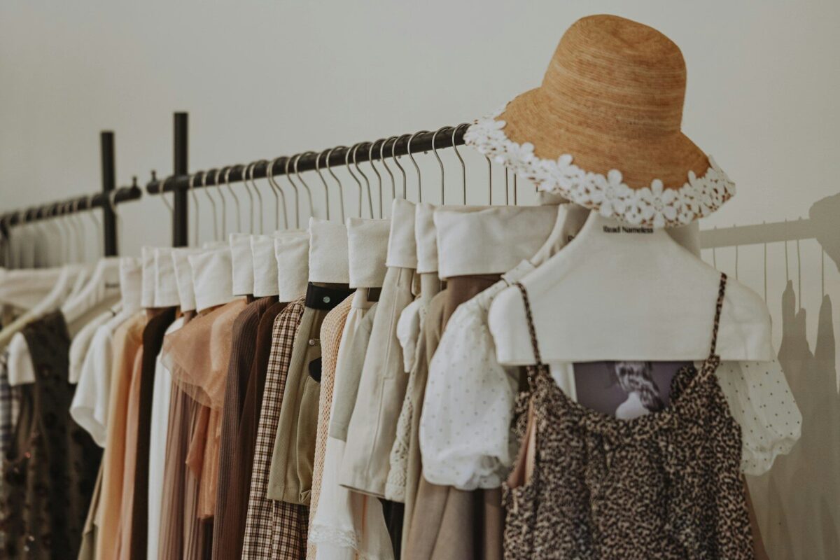 Clothes and straw hat on a clothing rack