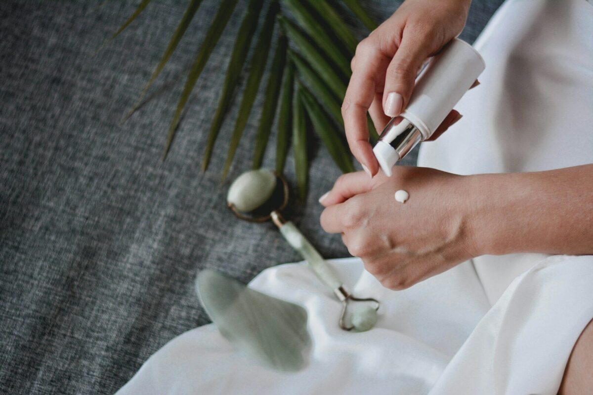 A person applying lotion to their hand with a jade roller and gua sha